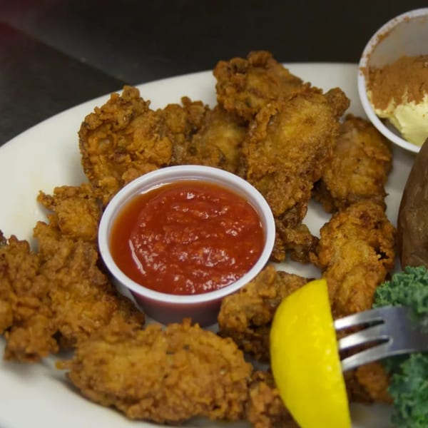 A plate of crispy fried chicken, a side of ketchup, and a lemon wedge at Sommer's Place.