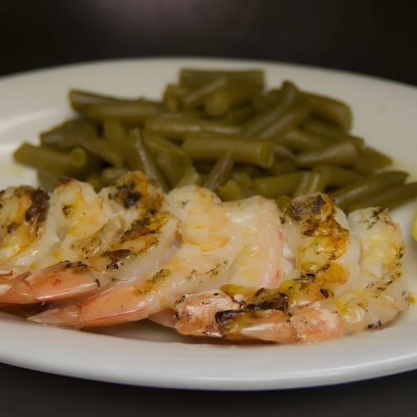 Grilled shrimp with visible char marks and green beans on a white plate at Sommer's Place.