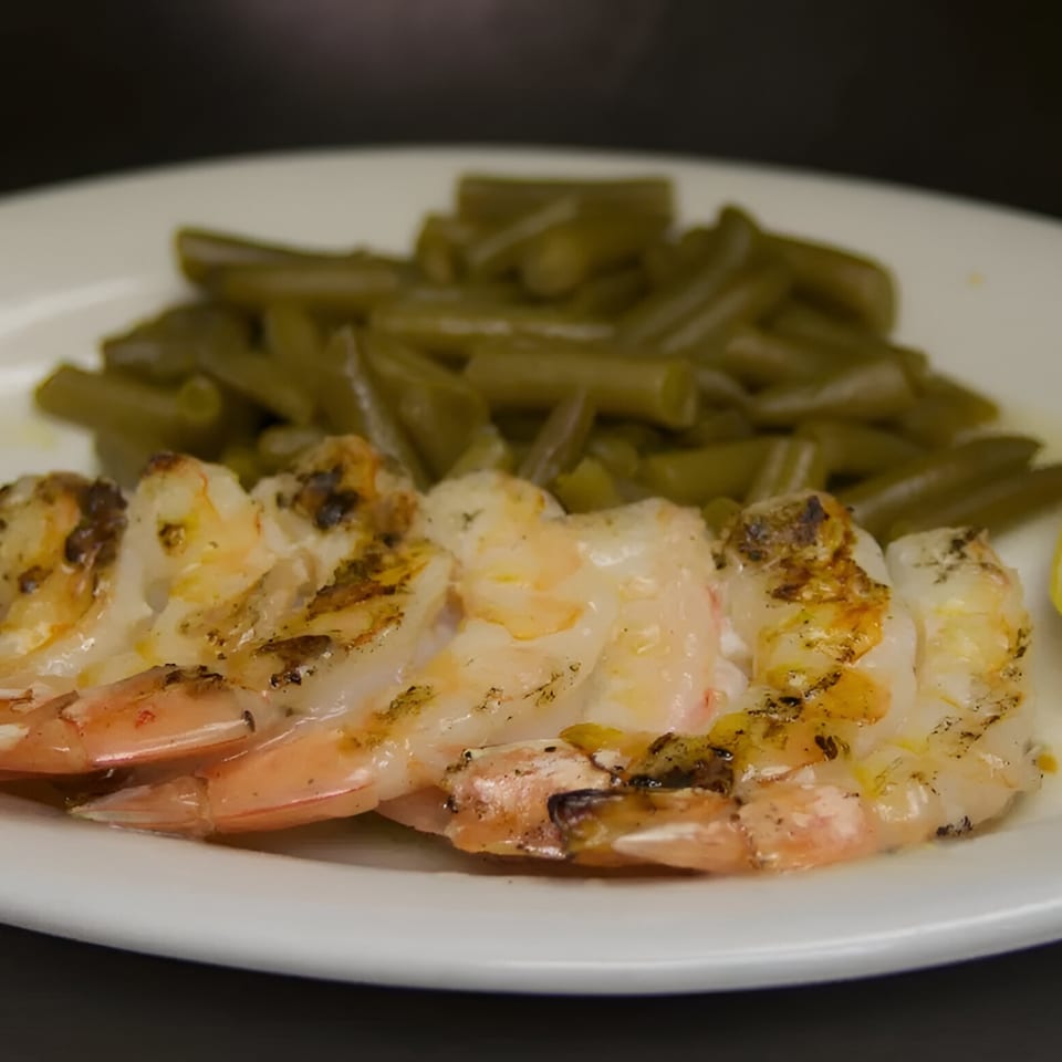 Grilled shrimp with visible char marks and green beans on a white plate at Sommer's Place.