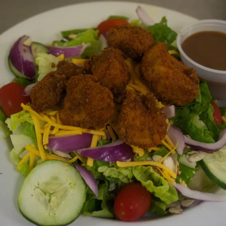 Sommer's Place southern fried chicken salad with lettuce, tomatoes, onions, cucumbers, cheese, and dressing.