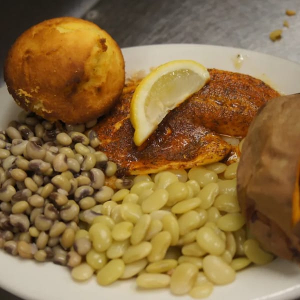 Southern-style plate with blackened fish, cornbread, black-eyed peas, lima beans, and a baked sweet potato.