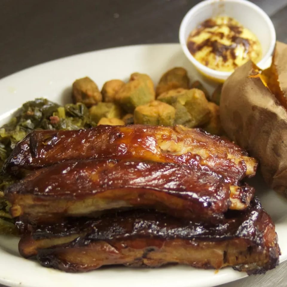 Sommer's Place southern meal with BBQ ribs, collard greens, fried okra, baked potato, and cheese sauce.