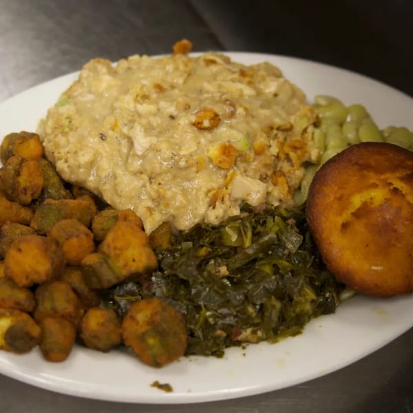 A southern meal with chicken and dressing, fried okra, collard greens, lima beans, and cornbread.